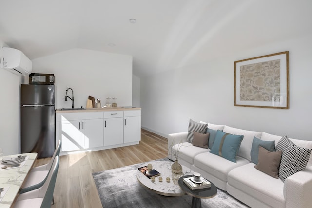 living room with light hardwood / wood-style floors, sink, a wall unit AC, and vaulted ceiling