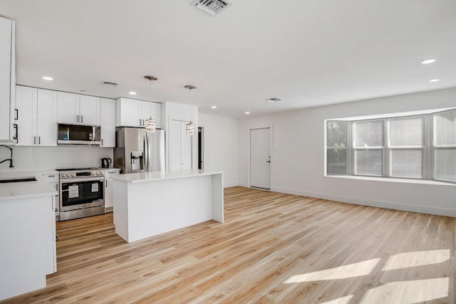 kitchen featuring pendant lighting, white cabinets, sink, appliances with stainless steel finishes, and a kitchen island