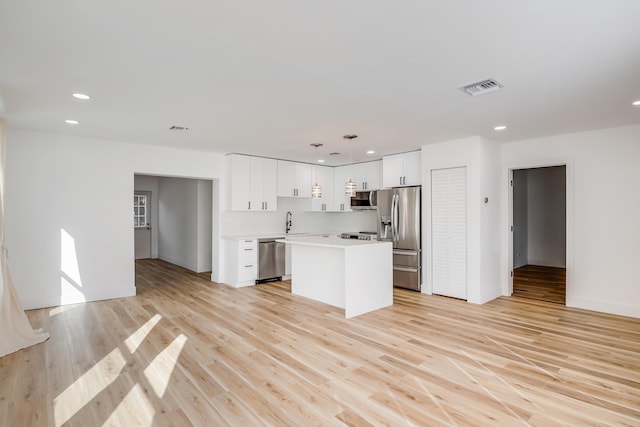 kitchen with pendant lighting, a center island, white cabinets, sink, and stainless steel appliances