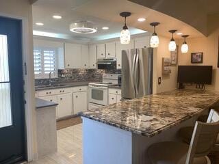 kitchen with stainless steel fridge, white cabinets, decorative light fixtures, and white stove