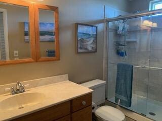 bathroom with vanity, toilet, and a shower with door