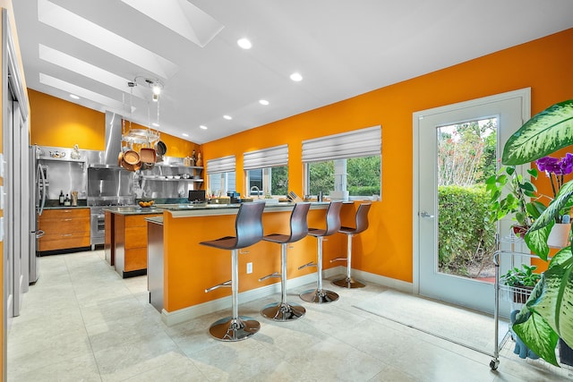 kitchen featuring pendant lighting, kitchen peninsula, a breakfast bar, and stainless steel fridge