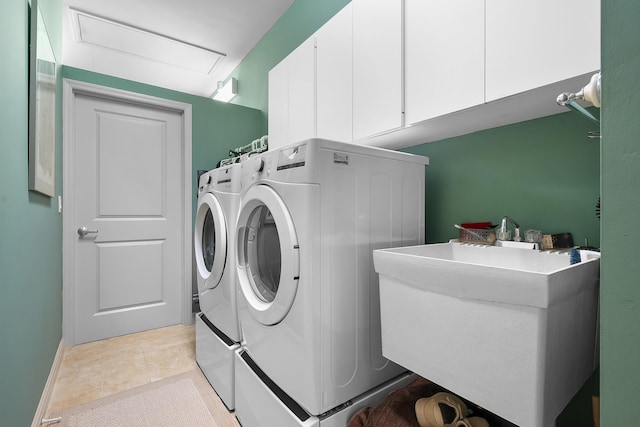 laundry area featuring cabinets, light tile patterned floors, washer and clothes dryer, and sink