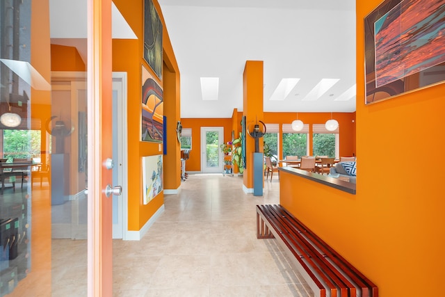 hallway featuring a skylight and high vaulted ceiling