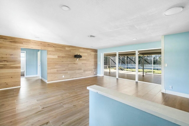 spare room featuring wooden walls, a textured ceiling, and hardwood / wood-style flooring