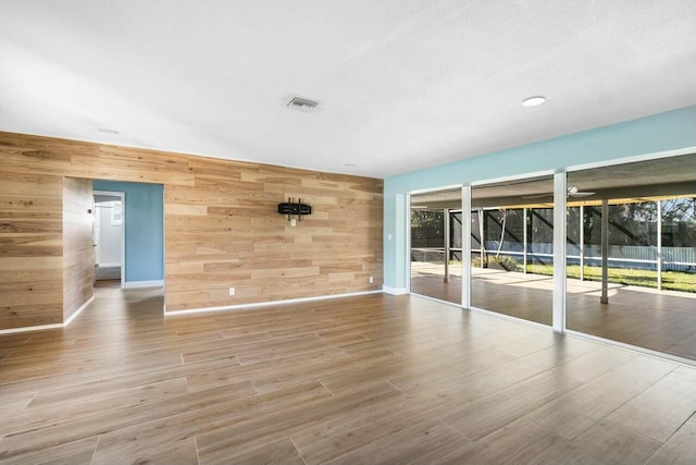 unfurnished room featuring light wood-type flooring and wooden walls