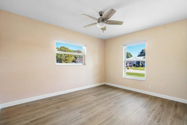 empty room with ceiling fan and light hardwood / wood-style flooring