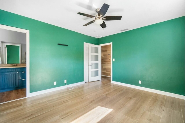 unfurnished bedroom with connected bathroom, ceiling fan, and light hardwood / wood-style flooring