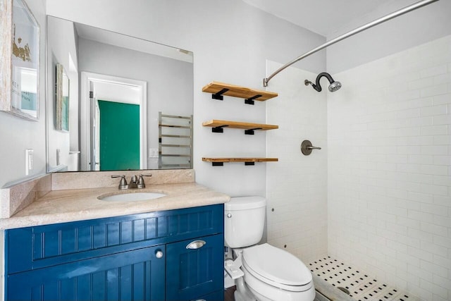 bathroom with a tile shower, vanity, and toilet