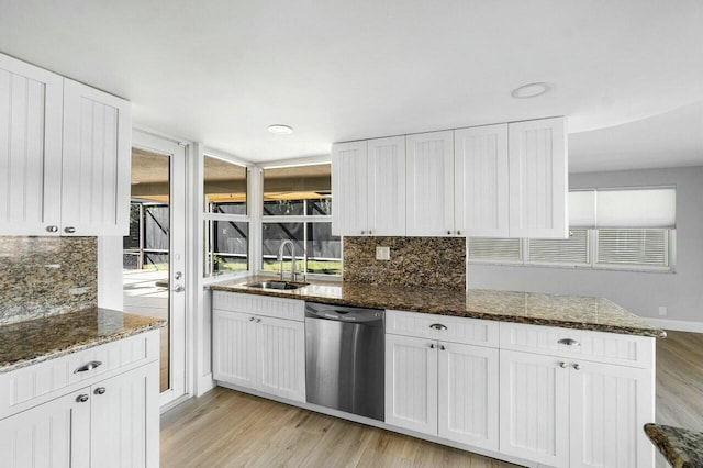 kitchen featuring dishwasher, white cabinets, sink, dark stone countertops, and light wood-type flooring