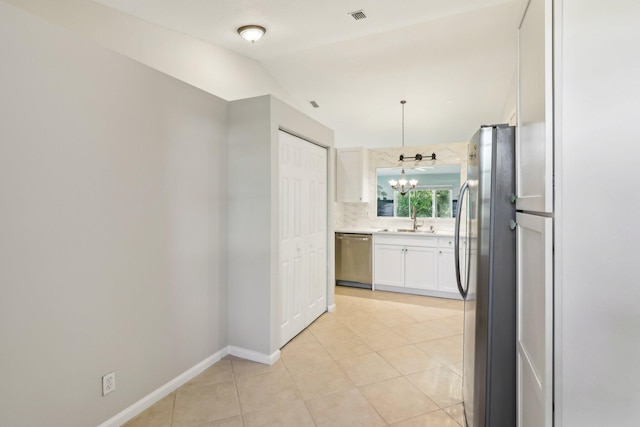 kitchen featuring lofted ceiling, a notable chandelier, sink, white cabinetry, and appliances with stainless steel finishes