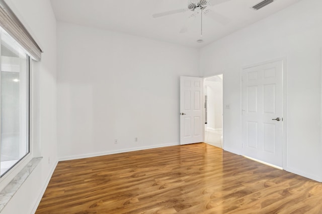 empty room featuring ceiling fan, a wealth of natural light, and wood-type flooring