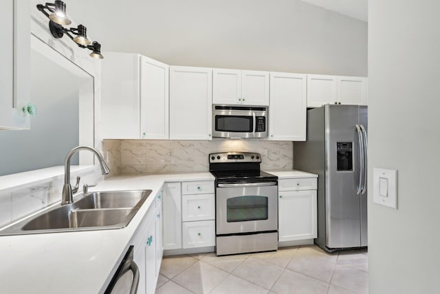 kitchen featuring appliances with stainless steel finishes, white cabinetry, decorative backsplash, sink, and light tile patterned flooring