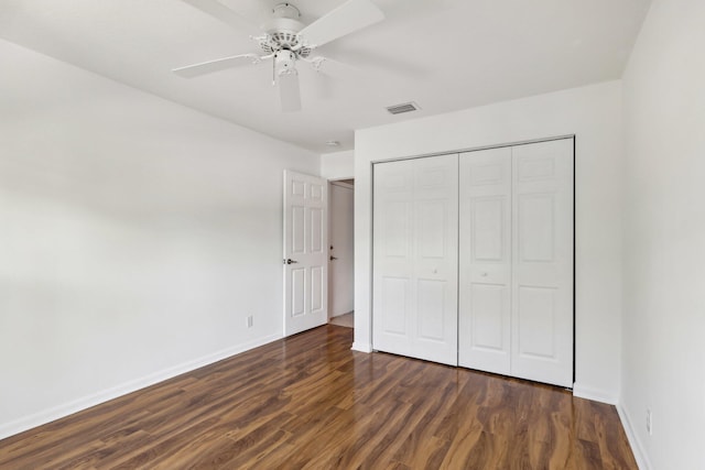 unfurnished bedroom with ceiling fan, dark wood-type flooring, and a closet