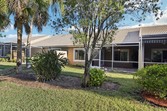 back of property featuring glass enclosure and a yard