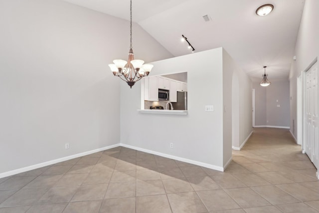 empty room with light tile patterned flooring, a notable chandelier, and vaulted ceiling