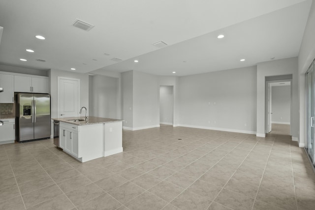 kitchen with appliances with stainless steel finishes, white cabinetry, a kitchen island with sink, and sink