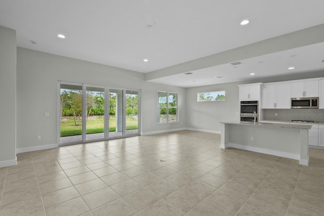 unfurnished living room featuring light tile patterned flooring and sink