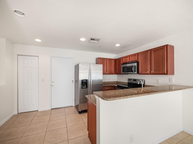 kitchen featuring kitchen peninsula, light tile patterned flooring, a textured ceiling, and appliances with stainless steel finishes