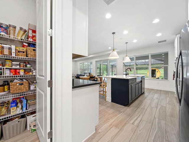 kitchen with pendant lighting, a breakfast bar, sink, an island with sink, and appliances with stainless steel finishes