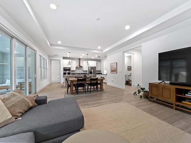 living room with a raised ceiling and light hardwood / wood-style flooring