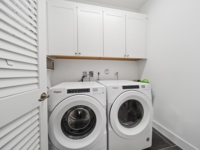 laundry room featuring washer and dryer, cabinets, and dark tile patterned flooring