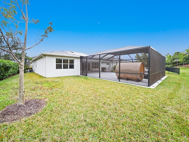 back of property featuring glass enclosure, a patio area, and a yard