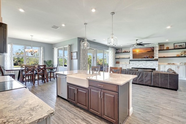 kitchen featuring pendant lighting, sink, stainless steel dishwasher, an island with sink, and dark brown cabinets