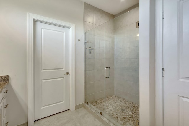 bathroom with tile patterned flooring, vanity, and walk in shower