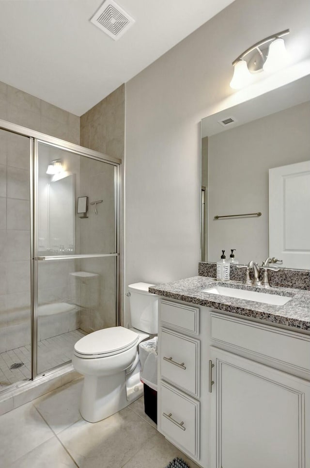 bathroom featuring tile patterned floors, vanity, toilet, and a shower with shower door