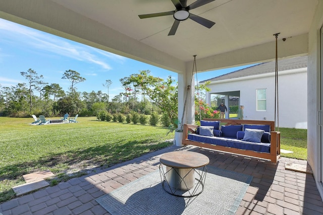 view of patio featuring ceiling fan and an outdoor living space with a fire pit