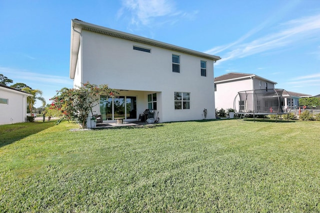 back of house with a trampoline, a yard, and a patio