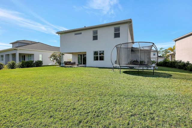 back of house with a lawn and a trampoline