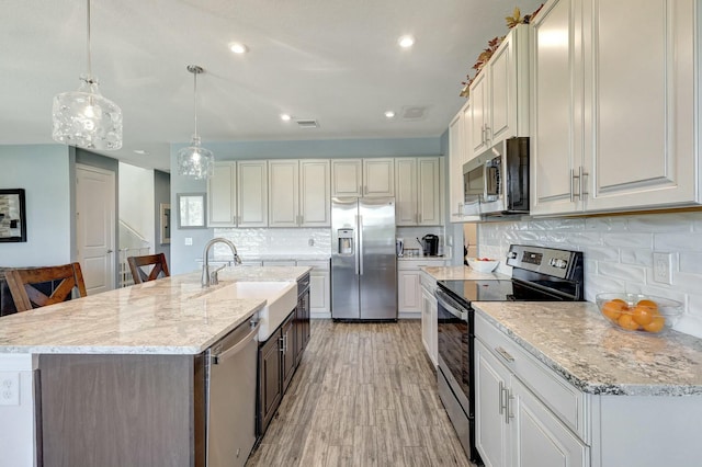 kitchen with white cabinets, sink, an island with sink, and stainless steel appliances