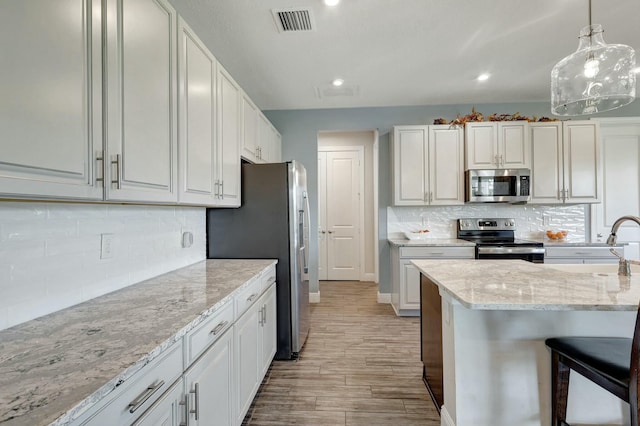 kitchen with white cabinets, decorative light fixtures, and appliances with stainless steel finishes