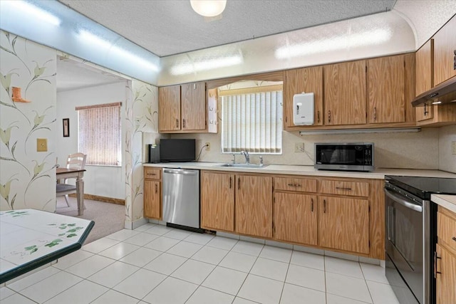 kitchen with a textured ceiling, stainless steel appliances, and sink