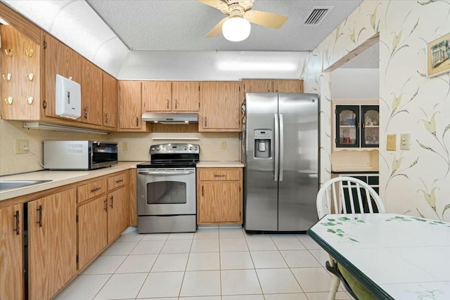 kitchen with ceiling fan, light tile patterned floors, stainless steel appliances, and a textured ceiling