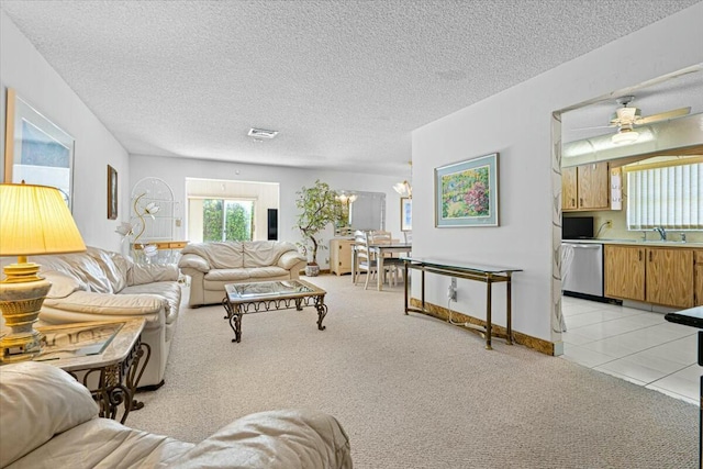 carpeted living room featuring a textured ceiling, sink, and ceiling fan with notable chandelier