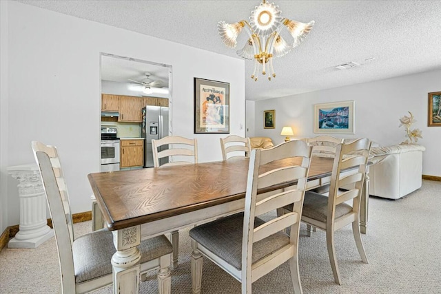 dining room featuring light carpet, ceiling fan with notable chandelier, and a textured ceiling