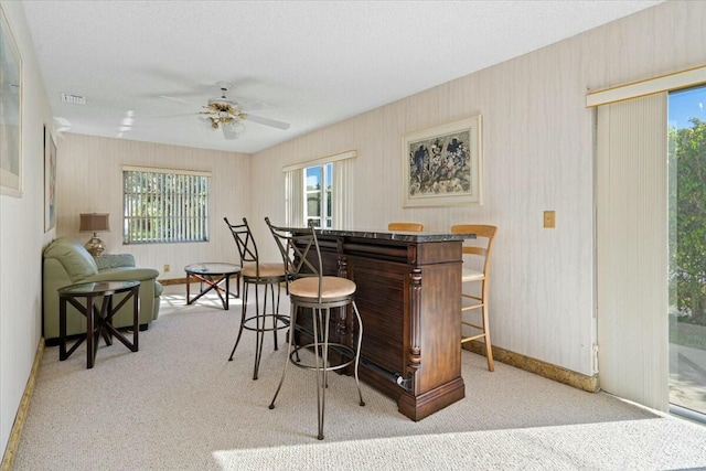 bar featuring ceiling fan and light carpet