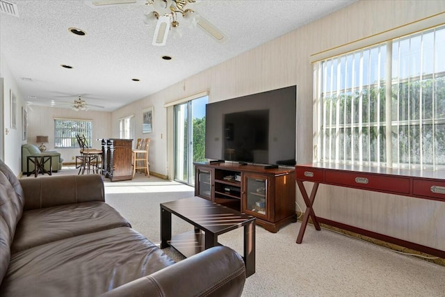 living room with ceiling fan, light colored carpet, and a textured ceiling