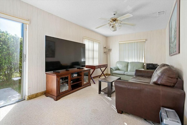 carpeted living room featuring ceiling fan and a textured ceiling