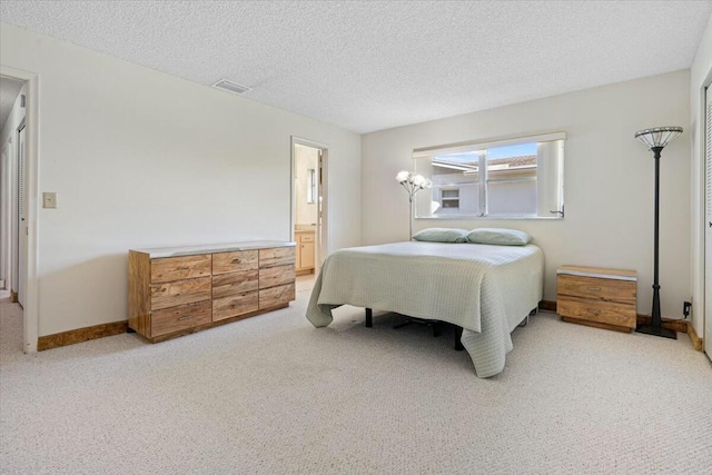 carpeted bedroom with a textured ceiling and ensuite bath