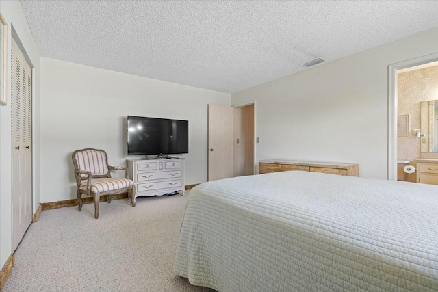 carpeted bedroom featuring ensuite bathroom, a closet, and a textured ceiling