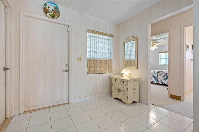 carpeted foyer featuring a textured ceiling and ceiling fan