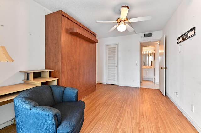 sitting room with ceiling fan, light hardwood / wood-style flooring, and a textured ceiling