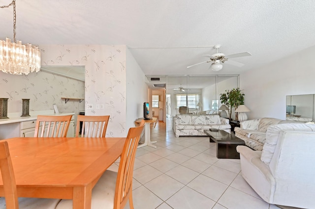 tiled dining room with ceiling fan with notable chandelier and a textured ceiling