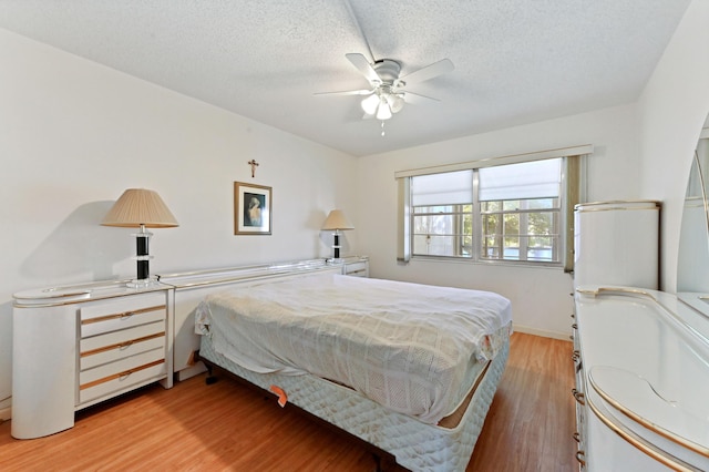 bedroom with a textured ceiling, light hardwood / wood-style flooring, and ceiling fan