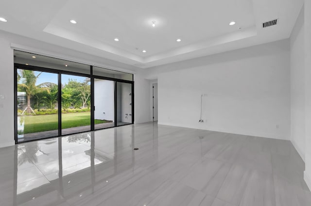 tiled spare room with a tray ceiling