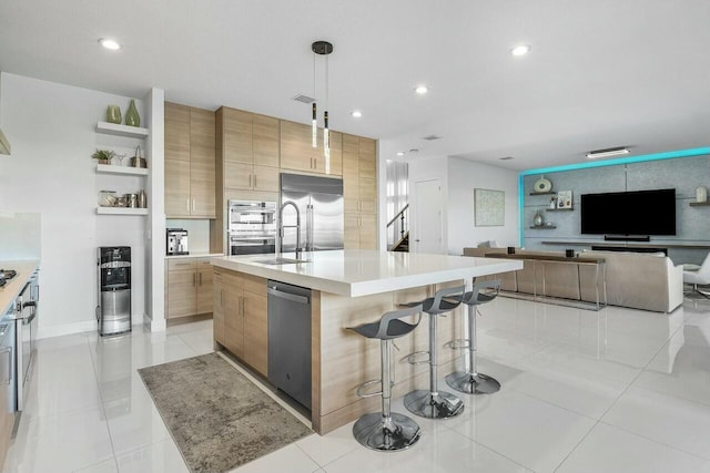 kitchen with pendant lighting, a breakfast bar, a center island with sink, light tile patterned floors, and appliances with stainless steel finishes